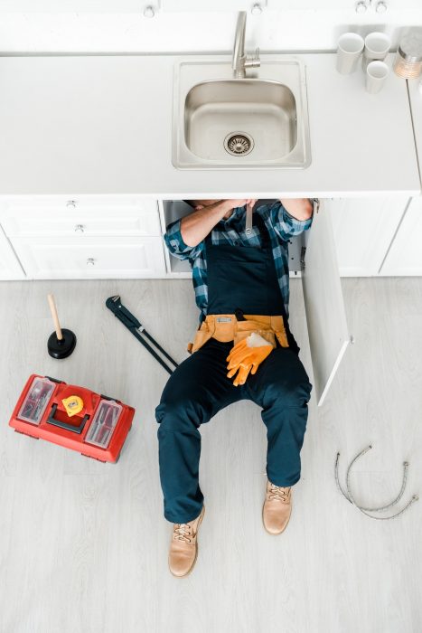 top view of handyman lying on floor while working near toolbox
